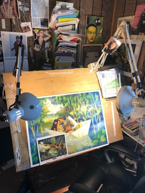 A photo of illustrator Raul Colon's workspace, featuring his painting easel with a work in progress: a scene of a man and woman in a boat.