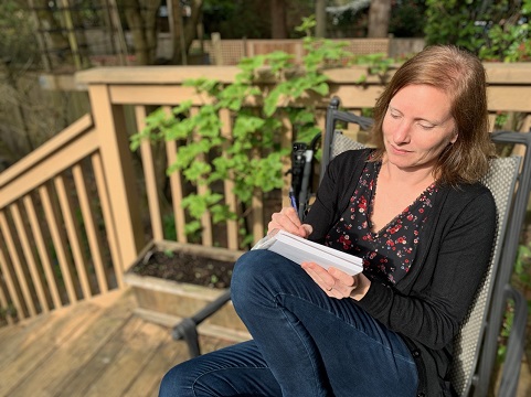 Author Tanya Lloyd Kyi writing on her outdoor deck.