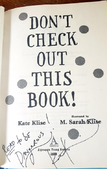 The title page of Don't Check Out This Book, signed by the author Kate Klise with the message, "Read to be dangerous!"