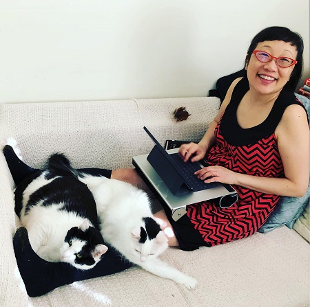 Paula Yoo with two of her cats lying on her legs.