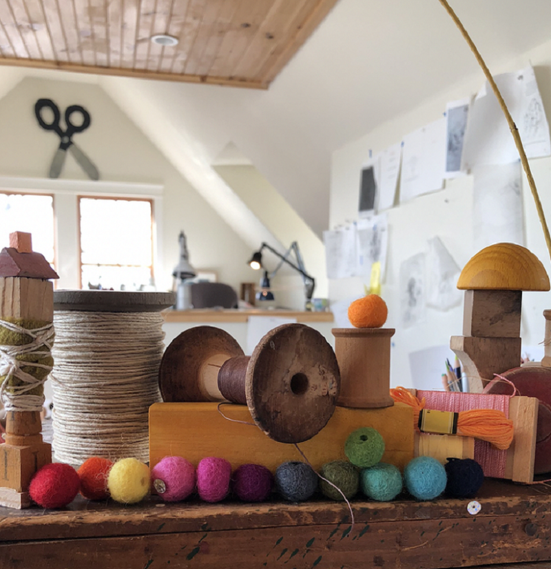 An interior image from Melissa Sweet's studio showing twine, brightly colored felt balls, wooden blocks, and other materials and inspiration for her artwork.