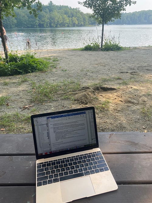 Author Gayle Forman's laptop, sitting on a table overlooking a lake scene.