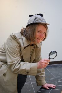 Dori Hillestad Butler wearing a Sherlock Holmes costume and holding a magnifying glass.