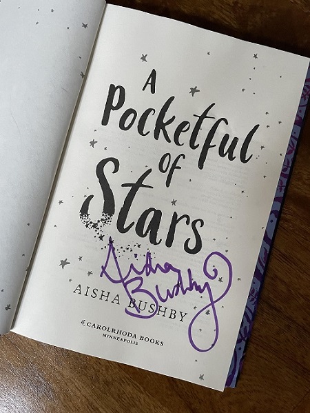 The title page of A Pocketful of Stars, signed by the author, Aisha Bushby.