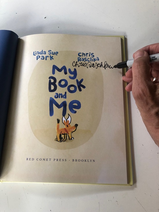 A photo of Chris Raschka's hand signing the title page of My Book and Me. 