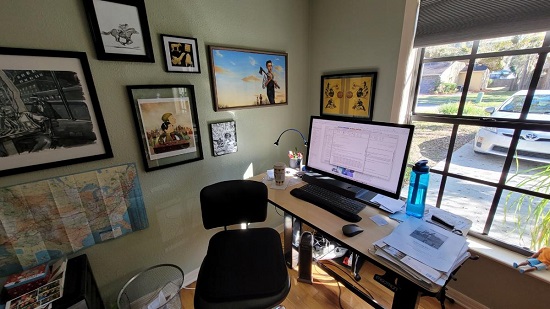 Author G. Neri's desk and computer in front of a sunny window.