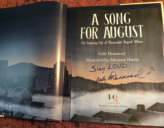 the title page of A Song for August signed by the author, Sally Denmead, with the message, "Sing Loud!"