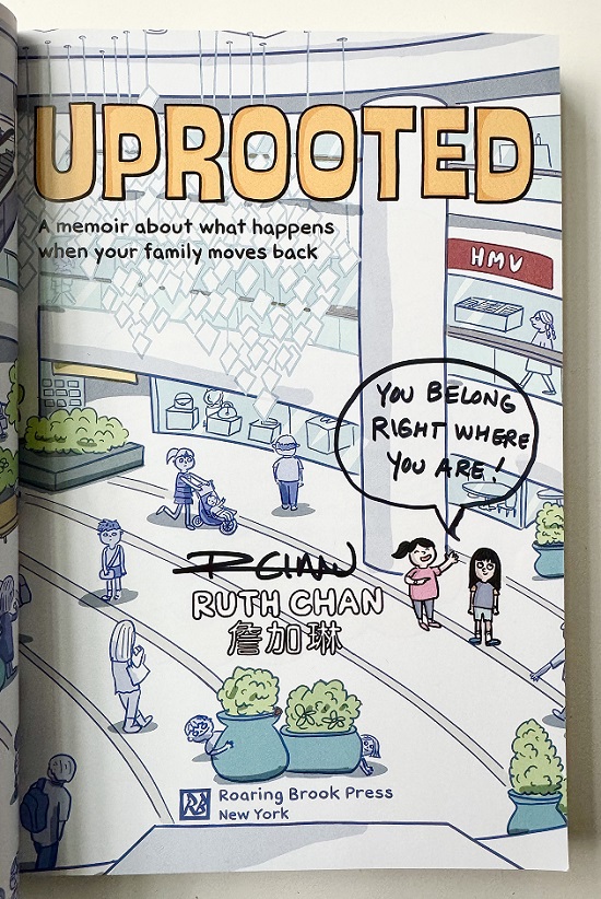 The title page from Uprooted, signed by the author, Ruth Chan. Inside a speech bubble are the words, "You belong right where you are!"