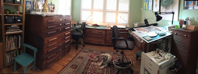 Marjorie Crosby-Fairall's studio, with narrow file drawers for art on the left side, and, on the right, a drafting table with a work in progress on it's surface.